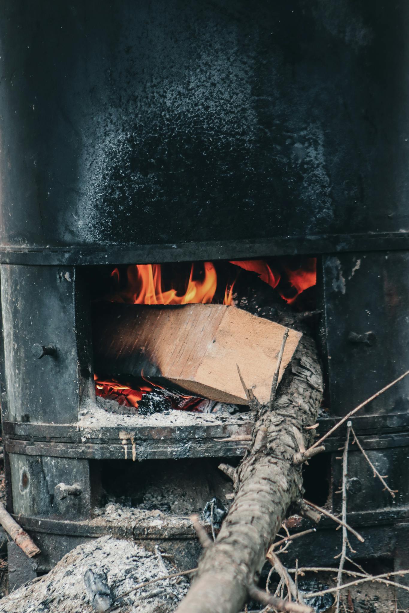Close-up of a wood burning stove with vibrant flames and ash residue.